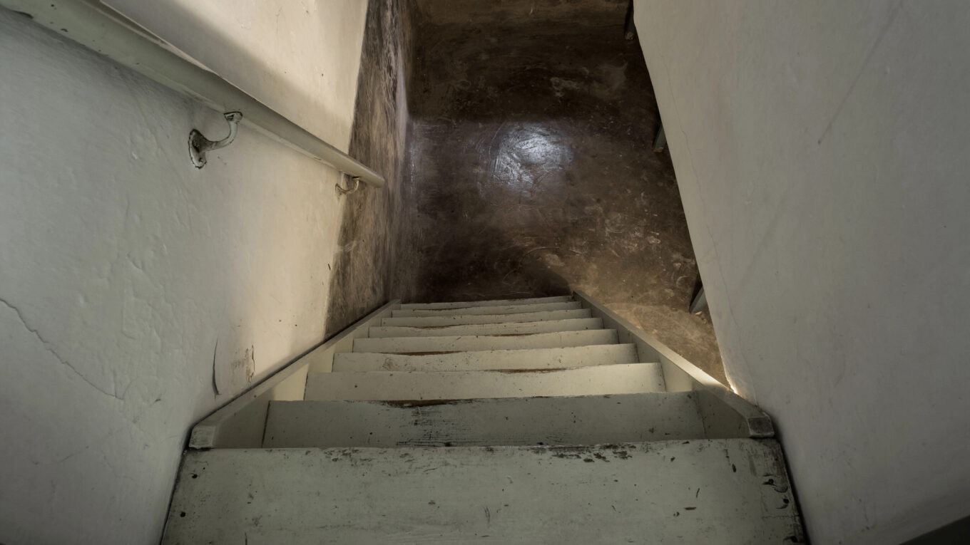 empty basement in abandoned old industrial building with little light and a wooden stairs