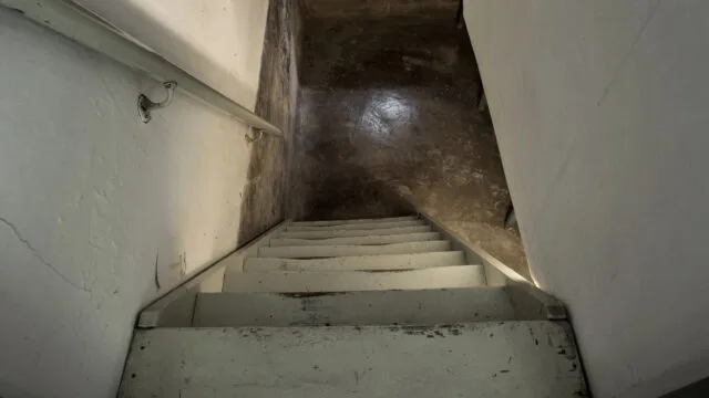 empty basement in abandoned old industrial building with little light and a wooden stairs