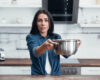 Amazed girl using steel pot during water leak in kitchen